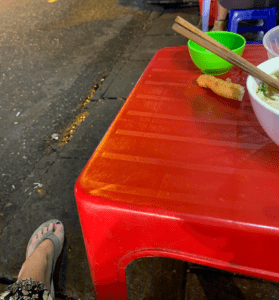 Tiny red table positioned inches from the busy street