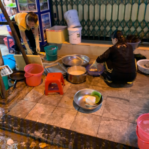 Restaurant workers washing dishes on sidewalk in Hanoi, Vietnam 