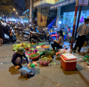 Street vendors spilling out on the sidewalk at night in Hanoi, Vietnam