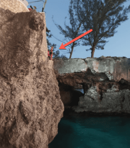 Bright red arrow pointing to the Hostel Mom before jumping from the high cliff