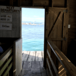 Small wooden building with a door open to the sea. The departure point from Caye Caulker, Belize