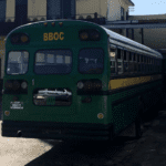 Green color school bus that is the primary transportation method in Belize