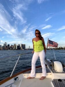 The Hostel Mom on the bow of a yacht with Manhattan skyline in background 