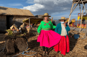 The Hostel Mom showing off a colorful skirt with a local on the floating islands of Uros on Lake Titicaca